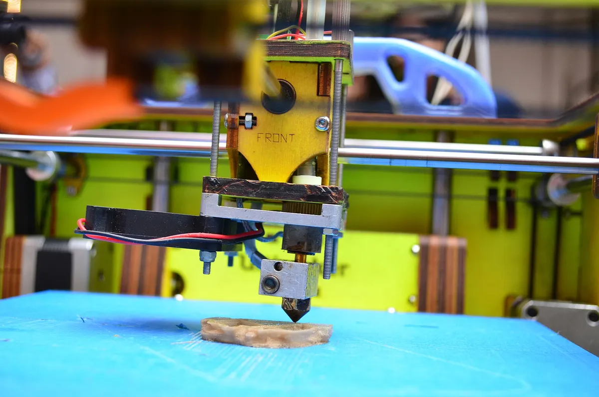 Bico de impressora 3D depositando filamento sobre uma peça em impressão